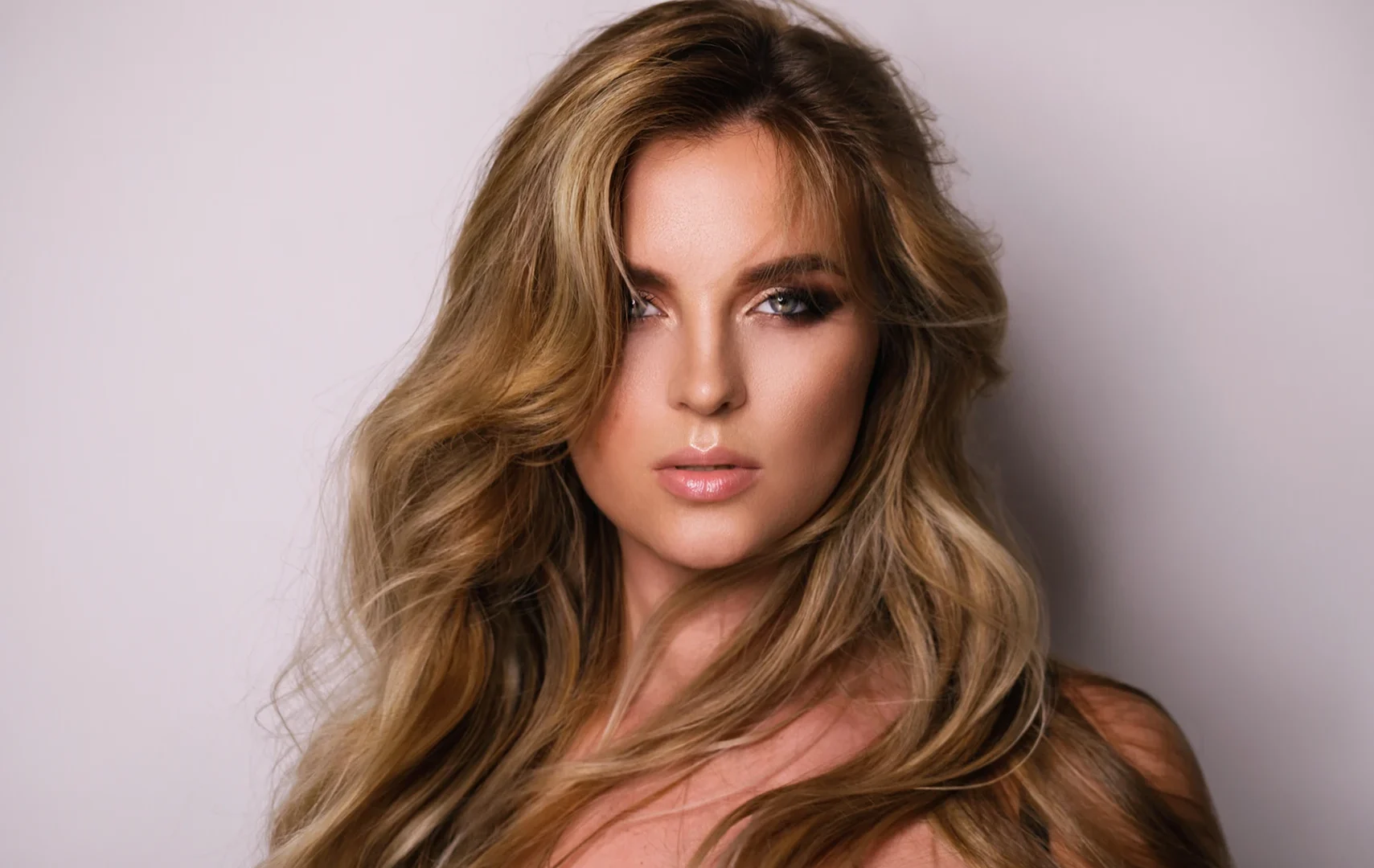 Imagen de una mujer módelo profesional de pelo largo luciendo un peinado con mechas Balayage en tonos dorados